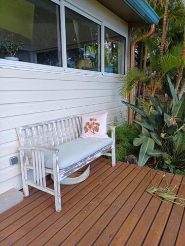 a white bench with a pink pillow sitting on a porch at Grande villa dans l'ouest - belle vue mer - piscine - jacuzzi - 4 chambres - jardin in Saint-Gilles-les Hauts