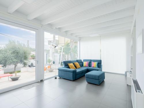 a living room with a blue couch and a large window at Villa Timpi Rossi Total Relax in Alcamo