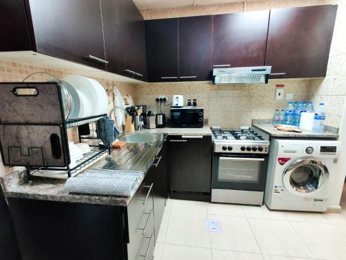 a kitchen with a stove and a washer and dryer at Elegant Fresh 1BR with Heated Pool, just steps from Mall, Restaurants & Fitness center in Dubai
