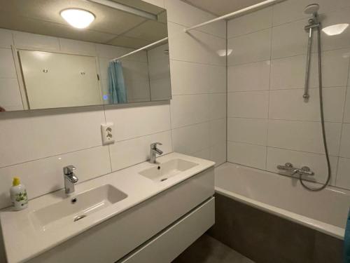 ein Badezimmer mit Waschbecken, Spiegel und Badewanne in der Unterkunft Strandparel 381 in Breskens
