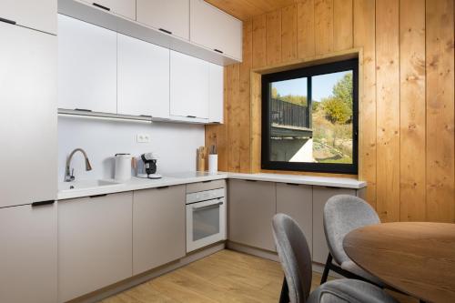 a kitchen with white cabinets and a table and a window at Chalet VLOčKA - Chalet Snowflake in Telgárt