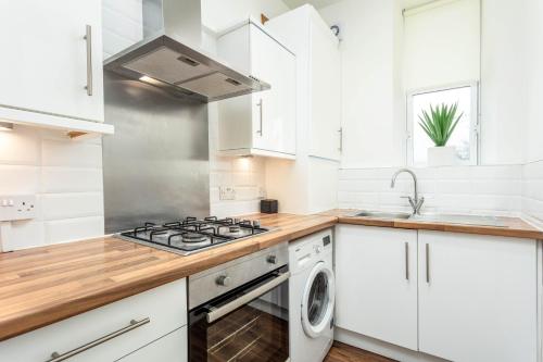 a white kitchen with a stove and a sink at Main Street View in Prestwick