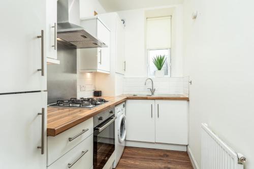 a white kitchen with white cabinets and a sink at Main Street View in Prestwick