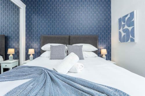 a bedroom with a large white bed with blue wallpaper at Main Street View in Prestwick