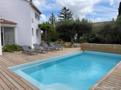 a swimming pool with lounge chairs next to a house at Villa Familiale avec Piscine proche de Sète et de Montpellier in Poussan