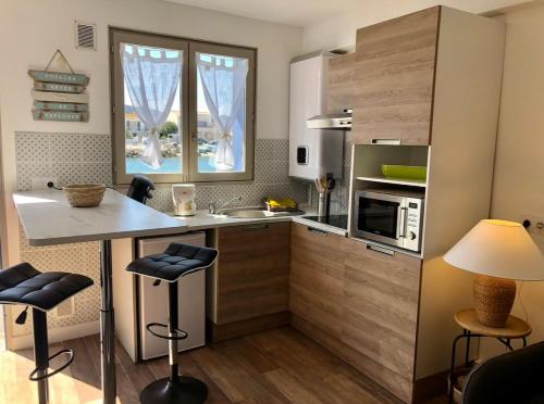 une cuisine avec un comptoir et un îlot de cuisine avec des tabourets dans l'établissement Petit nid coquet à la Pointe Courte, à Sète