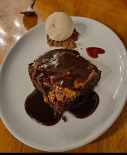 a white plate with a piece of chocolate cake and ice cream at Old Orleton Inn in Wellington