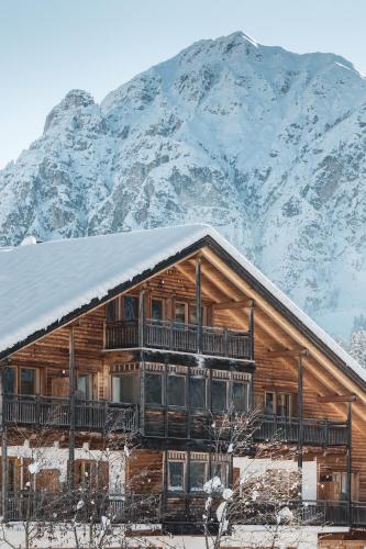 a log cabin with a snow covered mountain in the background at BergHotel Majarei in San Vigilio Di Marebbe