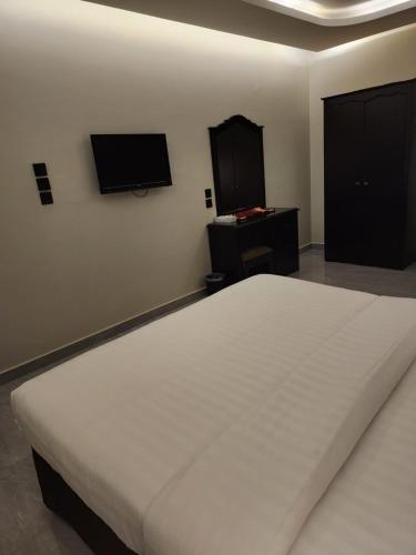 a bedroom with a white bed and a flat screen tv at شقق أمواج للشقق المخدومة in Al Khobar
