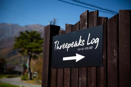 a sign with an arrow on a wooden fence at Three Peaks Log スリーピークス ログ in Hakuba