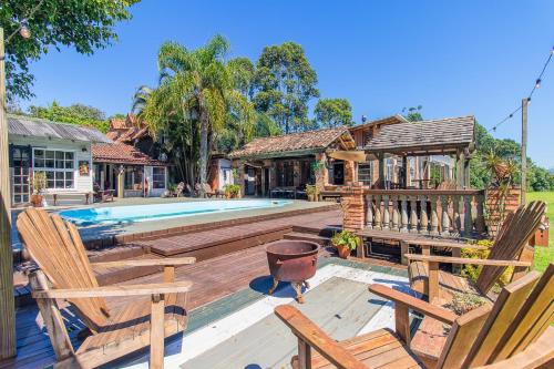 a house with a swimming pool and two chairs at Vieja Hacienda in Praia do Rosa