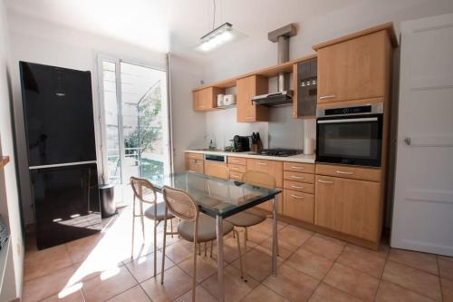 a kitchen with a glass table and chairs at Fé Di Biou - Jardin Parking Clim in Arles