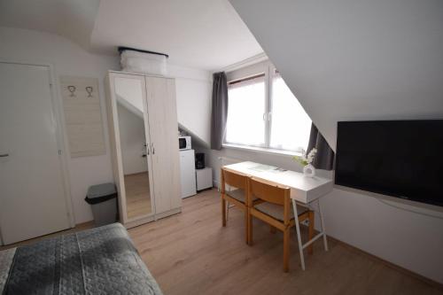 a room with a desk and a television and a bed at Omni Residence Vendégház in Bük