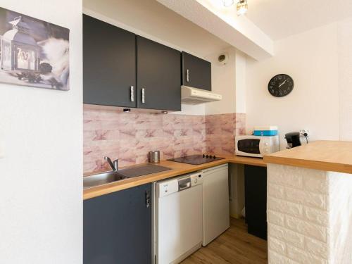 - une cuisine avec des placards noirs et un évier dans l'établissement Peyragudes : Appart 8 pers, balcon, parking, wifi - FR-1-695-51, à Germ