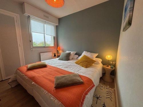 une chambre avec un grand lit avec une couverture orange dans l'établissement Quiberon - Appartement 3 pièces avec Balcon, Parking, Proche Plage et Centre-ville - FR-1-478-280, à Quiberon