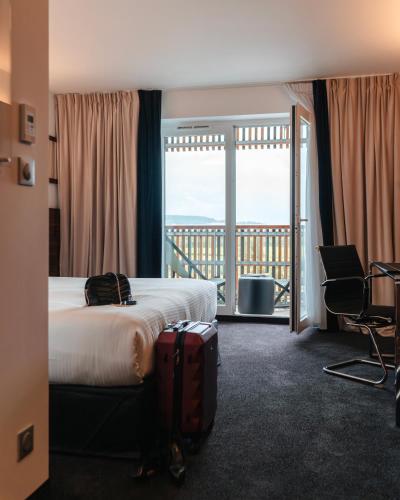 a hotel room with a bed and a balcony at Westotel Taverny - Paris Val-d'Oise in Taverny