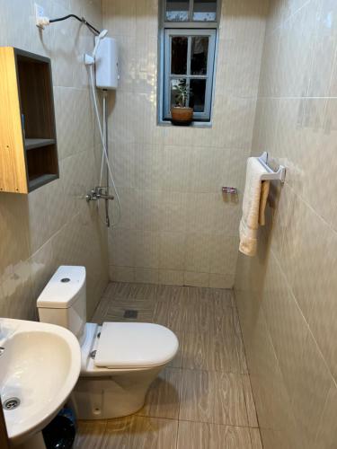 a bathroom with a toilet and a sink and a window at Live Well Rwanda House in Kigali