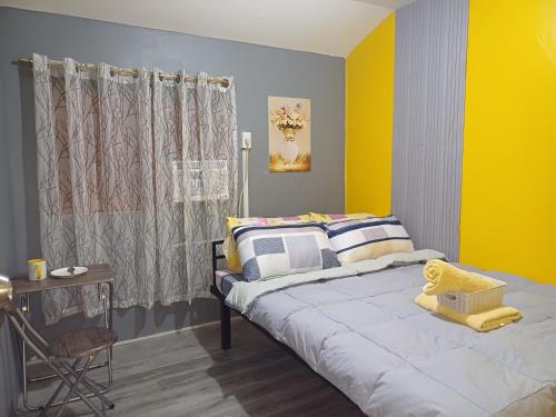a bedroom with a bed with a yellow wall at Fully-furnished House Near Puan, Bago & Baliok in Davao City in Davao City