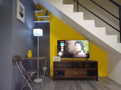 a living room with a tv on a cabinet under a staircase at Fully-furnished House Near Puan, Bago & Baliok in Davao City in Davao City