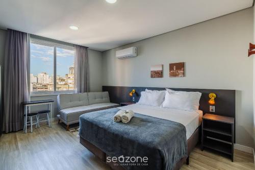 a hotel room with a bed and a couch at TCO - Apartamentos no Centro Histórico Porto Alegre/RS in Porto Alegre