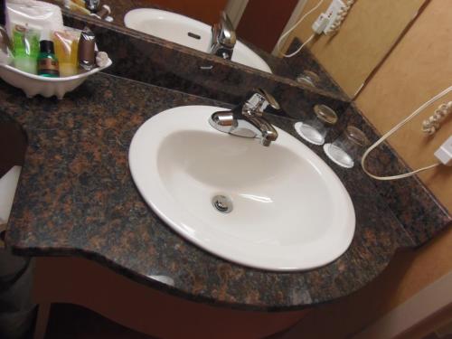 a bathroom counter with a white sink and a mirror at Rosslyn Inn & Suites in Edmonton