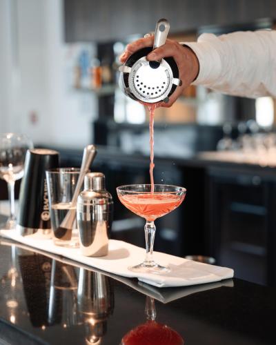 a person pouring a drink into a martini glass at Westotel Taverny - Paris Val-d'Oise in Taverny