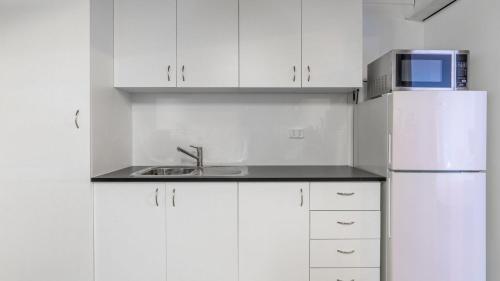 a white kitchen with a sink and a refrigerator at Bali Huts Escape in Nowra