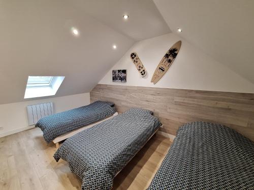 a room with two beds and a surfboard on the wall at Le Petit Chez Soi maison in Calais