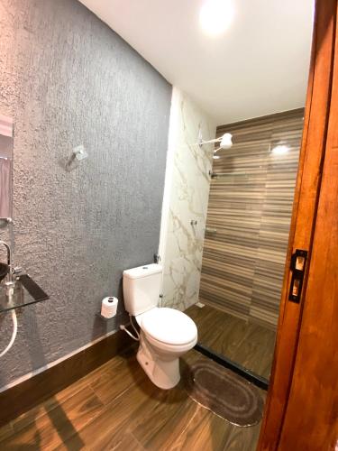 a bathroom with a white toilet and a shower at Pousada Recanto Beach House - Cabo Frio - RJ- Unamar- Cond Florestinha - 1 min a pé da praia in Tamoios