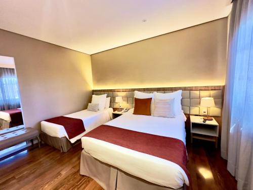 a hotel room with two beds and a window at Sanma Hotel in Foz do Iguaçu