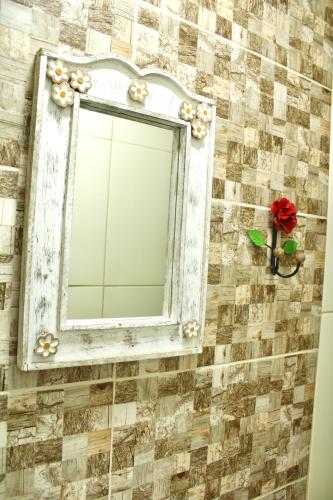 a mirror on a tiled wall with a red rose at Pousada Recanto Beach House - Cabo Frio - RJ- Unamar- Cond Florestinha - 1 min a pé da praia in Tamoios