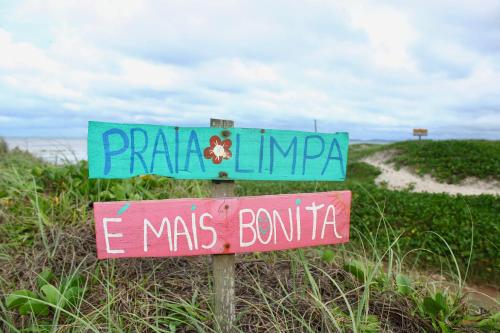 two street signs on a pole in front of a beach at Pousada Recanto Beach House - Cabo Frio - RJ- Unamar- Cond Florestinha - 1 min a pé da praia in Tamoios