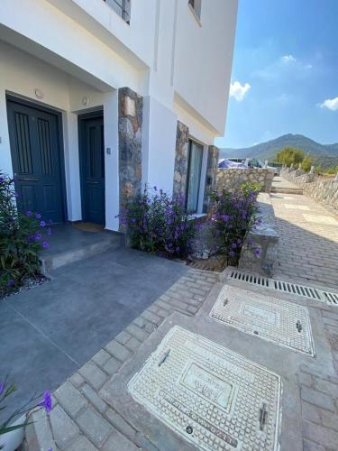 a building with a blue door and some purple flowers at Retreat, block B1, unit7 in Küçükerenköy