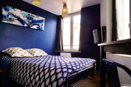 une chambre avec un lit avec un mur bleu dans l'établissement La cité des affaires, à Saint-Étienne