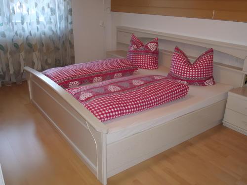 a bed with red and white pillows on it at Schwarzwalduhren Nescht Triberg in Triberg