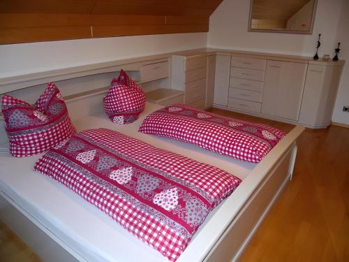 three red and white pillows sitting on a bed at Schwarzwalduhren Nescht Triberg in Triberg