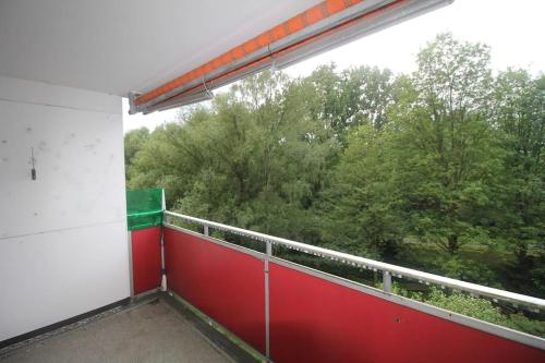 a balcony with a red and white railing and trees at Moderne und möblierte Wohnung! in Lünen