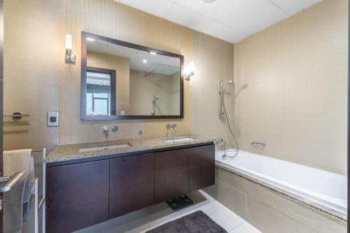 a bathroom with two sinks and a tub and a mirror at Emerald at Tiara Beach Residences with Atlantis views in Dubai