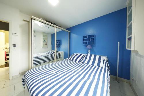 a blue bedroom with a striped bed and a mirror at Bretzel Home in Colmar