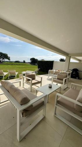 un patio con sillas blancas y una mesa y sillas blancas. en Appartement Jardin et Vue Golf, en San Roque