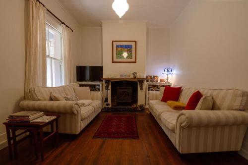 a living room with two couches and a fireplace at Larsens Cottage 2 - Historic 1880 Home in Mount Victoria