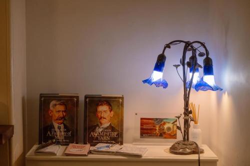 a desk with a lamp and pictures on it at Larsens Cottage 2 - Historic 1880 Home in Mount Victoria