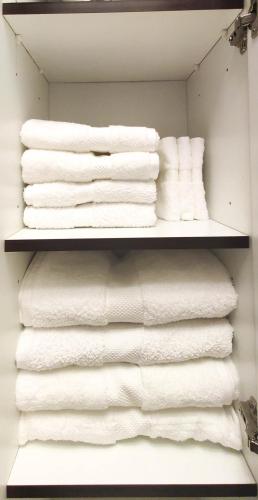 a closet filled with lots of white towels at Elegant Fresh 1BR with Heated Pool, just steps from Mall, Restaurants & Fitness center in Dubai