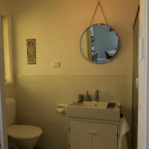 a bathroom with a sink and a toilet and a mirror at Harmonica - unique modern chic apartment in Katoomba