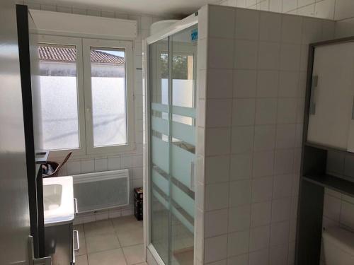 une salle de bain avec une douche et un lavabo et une fenêtre dans l'établissement appartement la teste centre, à La Teste-de-Buch