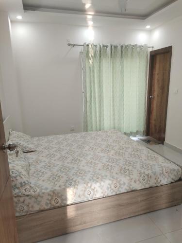 a bedroom with a bed and a window with a bedspread at The feathers in Rājpur