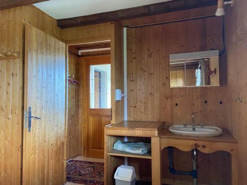 La salle de bains en bois est pourvue d'un lavabo et d'un miroir. dans l'établissement Chalet cosy à Crest-Voland – 6 personnes, cuisine équipée, salon TV, proche pistes et nature - FR-1-733-154, à Crest-Voland