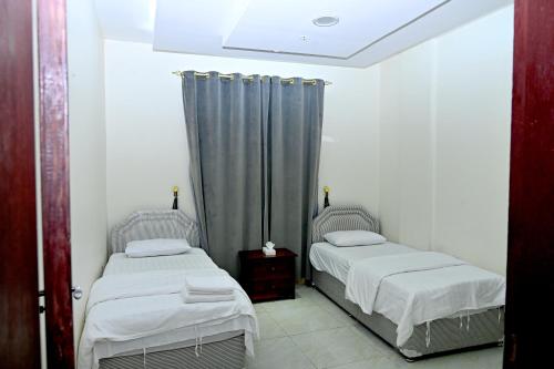 two twin beds in a room with a window at Durrat Alkhuwair Hotel Apartment درة الخوير للشقق الفندقية in Muscat