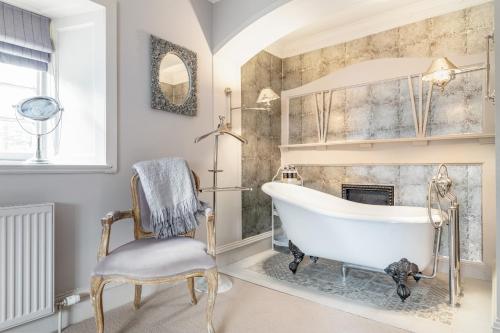 baño con bañera, silla y chimenea en Unique Arts & Crafts Home in Auchterarder, en Auchterarder