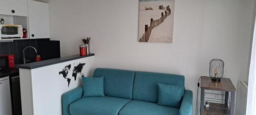 un salon avec un canapé bleu et une table dans l'établissement Studio à moins de 50m de l'école de voile..., à La Turballe